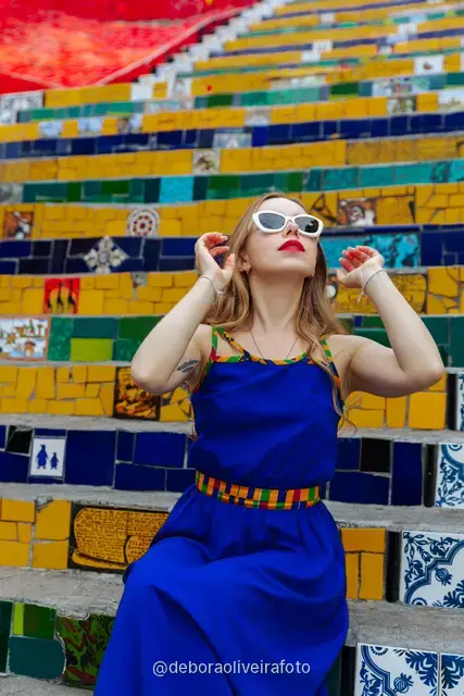 Woman in a blue dress sitting on the colorful tiled Selarón Steps in Santa Teresa, Rio de Janeiro