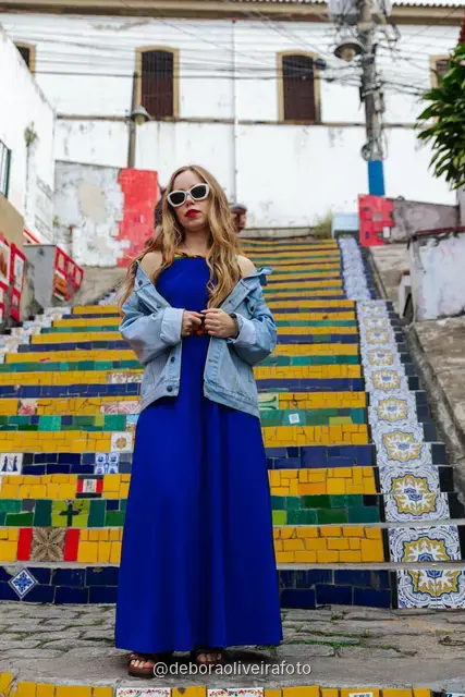 Woman in a blue dress sitting on the colorful tiled Selarón Steps in Santa Teresa, Rio de Janeiro