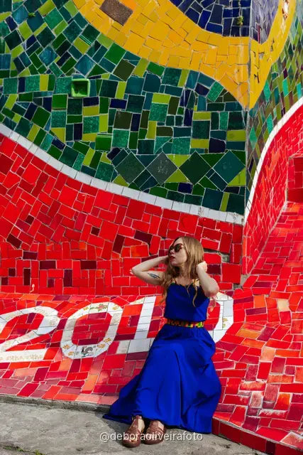 Woman in a blue dress sitting on the colorful tiled Selarón Steps in Santa Teresa, Rio de Janeiro
