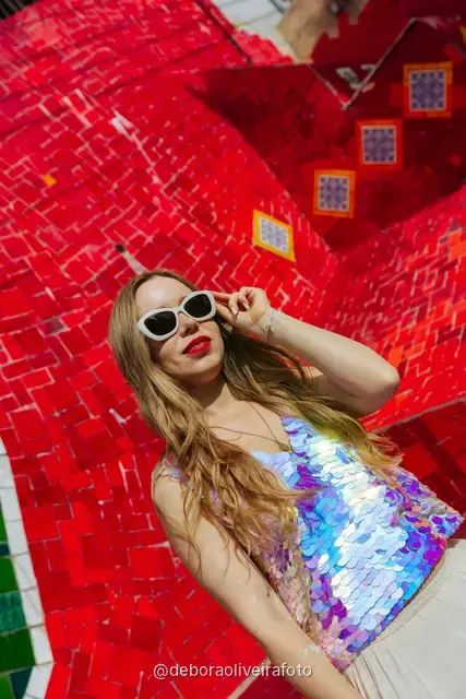 Woman in a sequin top in front of the red tile wall at the Selarón Steps, and a green coconut on a graffiti street corner
