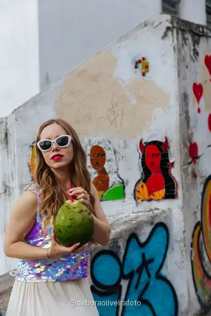 Woman in a sequin top in front of the red tile wall at the Selarón Steps, and a green coconut on a graffiti street corner