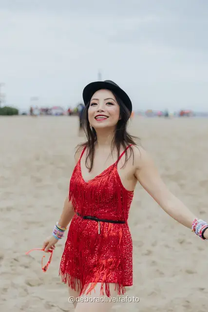Mujer con enterizo corto de flecos rojos, sombrero y gafas rojas en la vereda de olas de Copacabana, en Río de Janeiro
