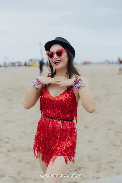 Mujer con enterizo corto de flecos rojos, sombrero y gafas rojas en la vereda de olas de Copacabana, en Río de Janeiro