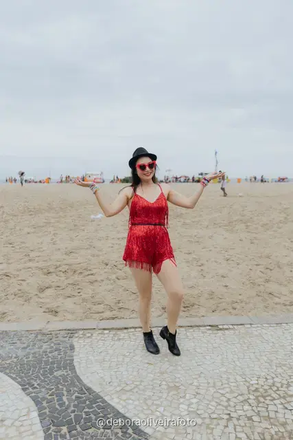 Mujer con enterizo corto de flecos rojos, sombrero y gafas rojas en la vereda de olas de Copacabana, en Río de Janeiro