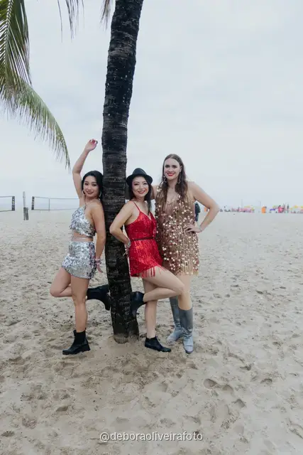 Persona con look de lentejuelas plateado y dorado junto a una palmera en la arena de Copacabana, en Río de Janeiro