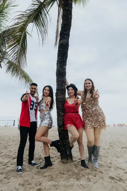 Persona con look de lentejuelas plateado y dorado junto a una palmera en la arena de Copacabana, en Río de Janeiro