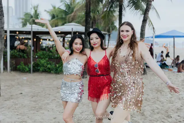 Group of four people in sequin outfits walking and jumping on the avenue at Copacabana in Rio de Janeiro