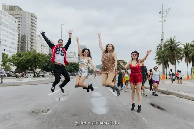 Grupo de cuatro personas con looks de lentejuelas caminando y saltando en la avenida de Copacabana, en Río de Janeiro