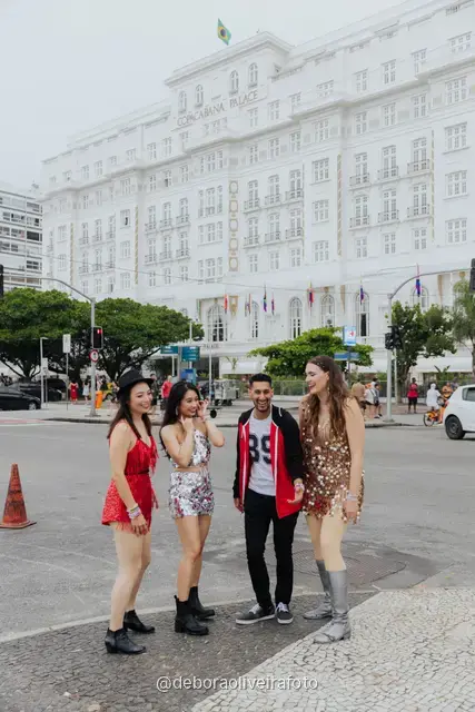 Grupo de cuatro personas con looks de lentejuelas caminando y saltando en la avenida de Copacabana, en Río de Janeiro