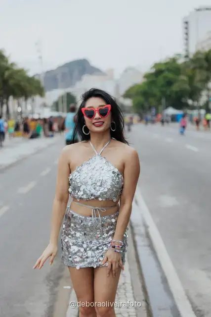 Individual portrait in a sequin outfit on the median of the avenue at Copacabana with the mountains behind