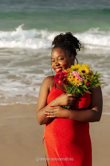 Woman in a red dress running and walking on Ipanema Beach with sunflowers under a cloudy sky