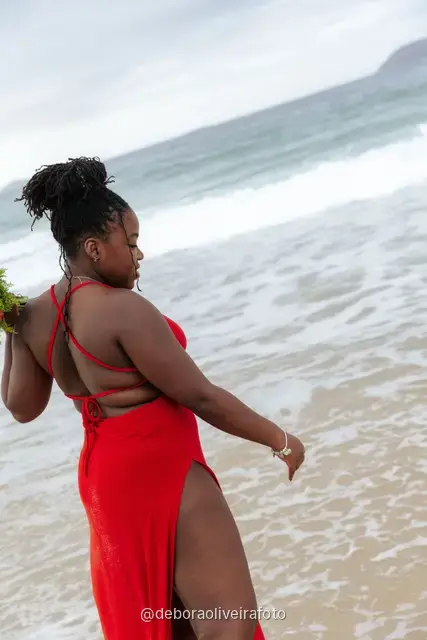 Woman in a red dress playing in the waves of Ipanema Beach in Rio de Janeiro