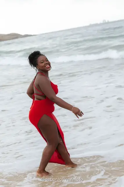 Woman in a red dress playing in the waves of Ipanema Beach in Rio de Janeiro