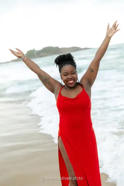 Woman in a red dress playing in the waves of Ipanema Beach in Rio de Janeiro