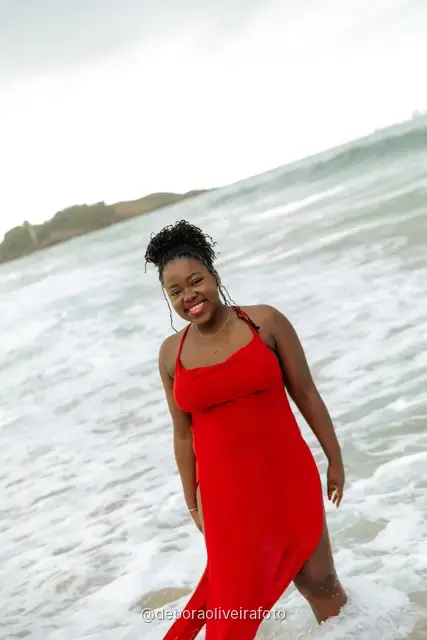 Woman in a red dress playing in the waves of Ipanema Beach in Rio de Janeiro
