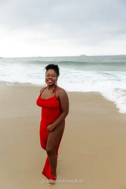 Woman in a red dress playing in the waves of Ipanema Beach in Rio de Janeiro