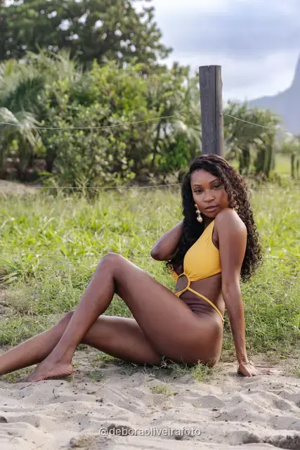 Woman in a yellow swimsuit on the Ipanema promenade with the Two Brothers mountain behind