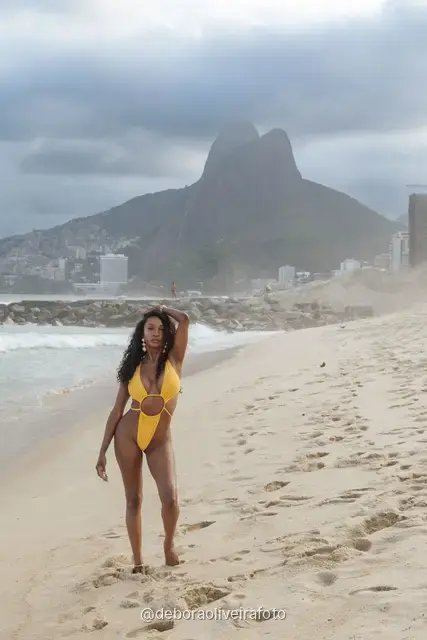 Mulher de maiô amarelo na praia de Ipanema com o Morro Dois Irmãos ao fundo