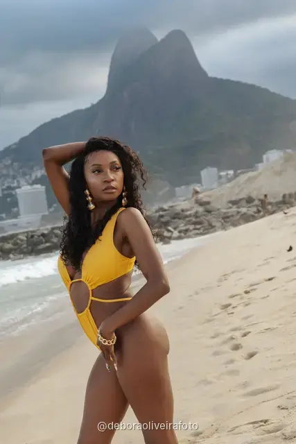 Woman in a yellow swimsuit on Ipanema Beach with the Two Brothers mountain behind