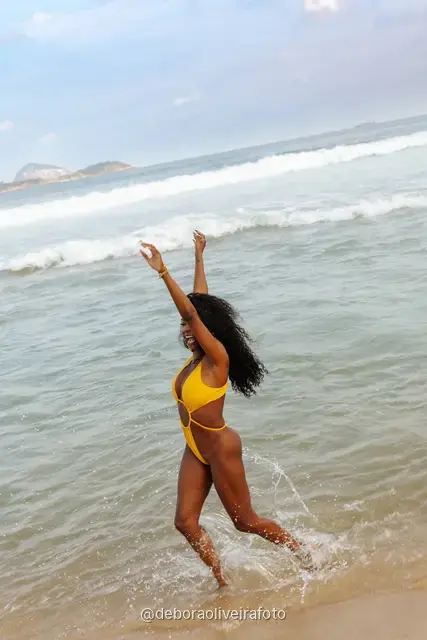 Mulher de maiô amarelo brincando nas ondas da praia de Ipanema