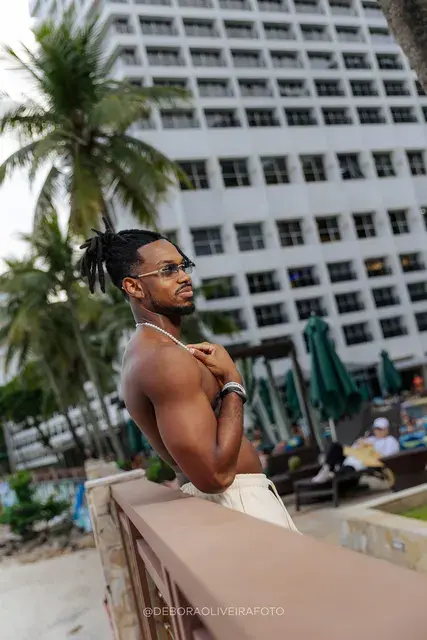 Homem de calça de linho clara no deck e na areia de um hotel de frente para o mar no Rio de Janeiro