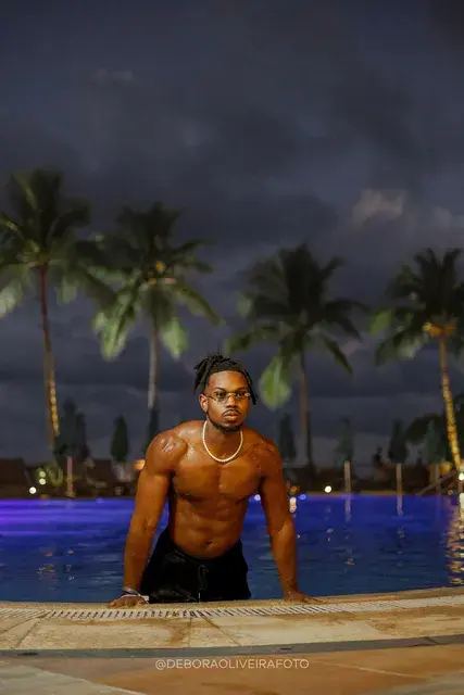 Homem fotografado à noite junto à piscina e às luzes do deck de um hotel no Rio de Janeiro