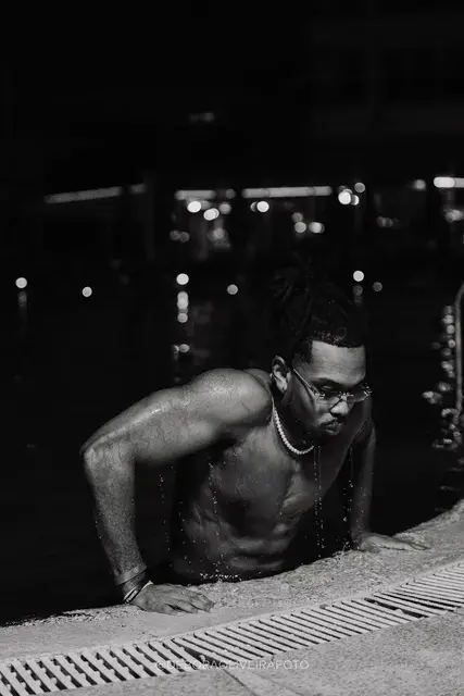 Homem fotografado à noite junto à piscina e às luzes do deck de um hotel no Rio de Janeiro