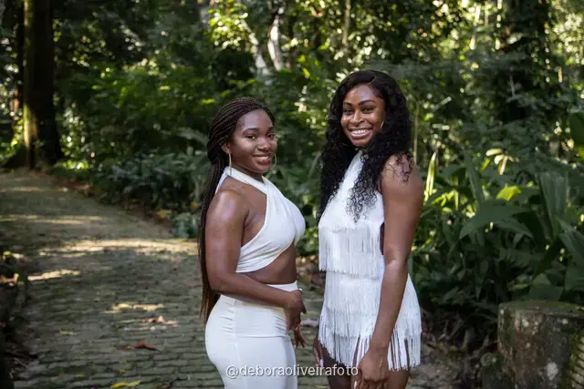 Two women in white outfits walking on a stone path in the forest of Parque Lage in Rio de Janeiro