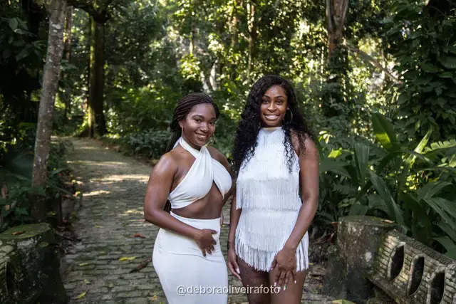 Two women in white outfits walking on a stone path in the forest of Parque Lage in Rio de Janeiro