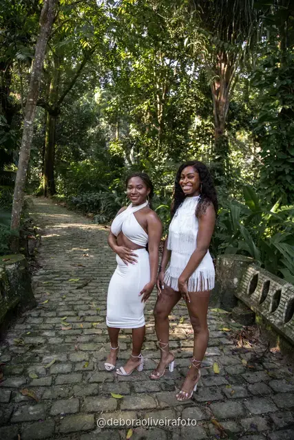Two women in white outfits walking on a stone path in the forest of Parque Lage in Rio de Janeiro