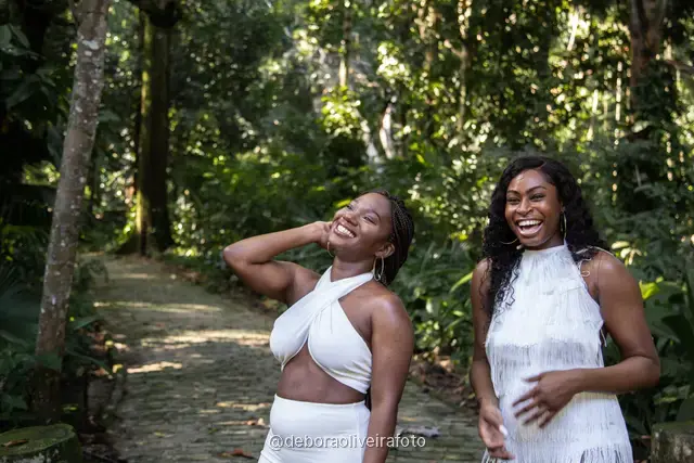 Two women in white outfits walking on a stone path in the forest of Parque Lage in Rio de Janeiro