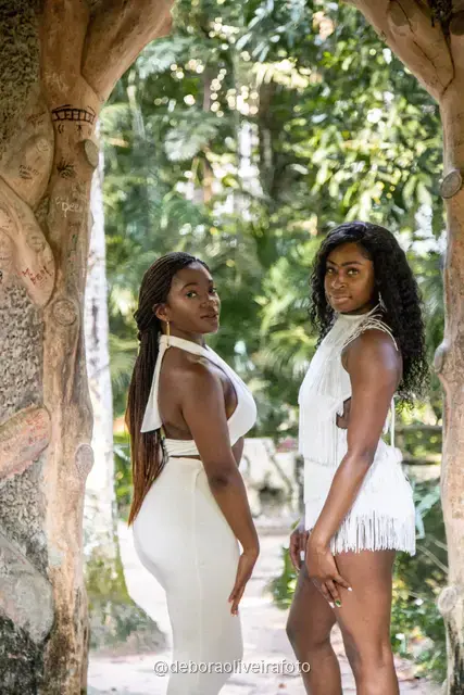 Two women in white among big leaves, forest steps and a ruined stone arch at Parque Lage