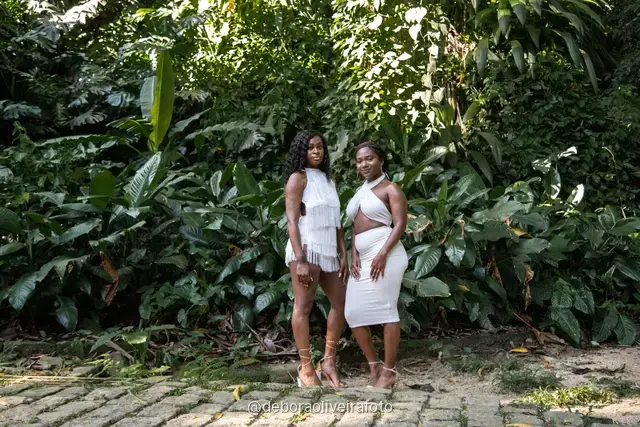 Two women in white among big leaves, forest steps and a ruined stone arch at Parque Lage