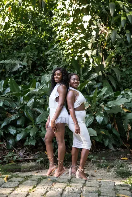 Two women in white among big leaves, forest steps and a ruined stone arch at Parque Lage