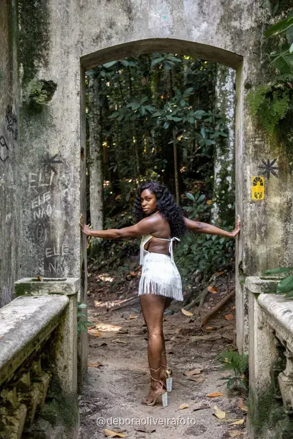Two women in white among big leaves, forest steps and a ruined stone arch at Parque Lage