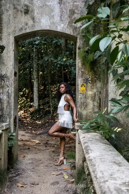 Two women in white among big leaves, forest steps and a ruined stone arch at Parque Lage