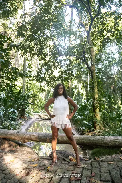 Two women in white sitting on the old bridge and on a fallen log at Parque Lage in Rio de Janeiro