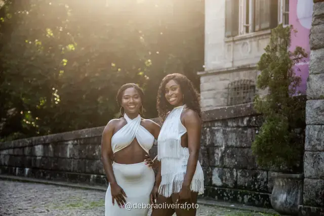 Two women in white in the garden in front of the Parque Lage mansion with the mountain behind