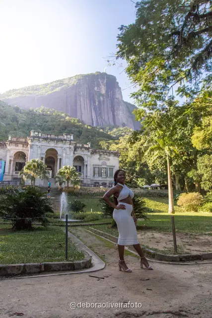 Two women in white in the garden in front of the Parque Lage mansion with the mountain behind