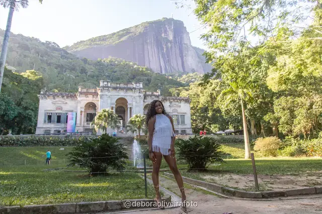 Two women in white in the garden in front of the Parque Lage mansion with the mountain behind