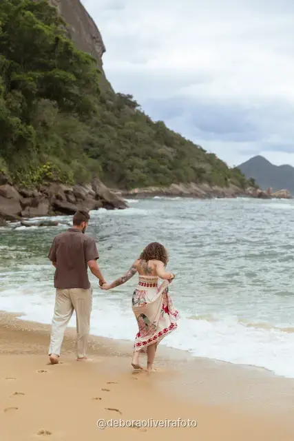 Couple walking and dancing at the water line of Praia Vermelha with Sugarloaf Mountain behind