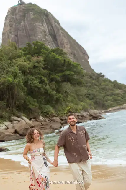 Couple walking and dancing at the water line of Praia Vermelha with Sugarloaf Mountain behind