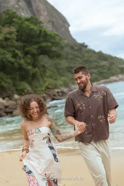 Pareja caminando y bailando en la orilla de Praia Vermelha con el Pan de Azúcar detrás