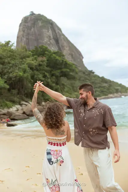 Couple walking and dancing at the water line of Praia Vermelha with Sugarloaf Mountain behind