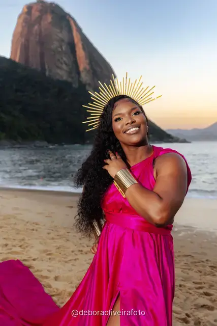 Woman in a pink flying dress at Praia Vermelha at sunset with Sugarloaf Mountain behind