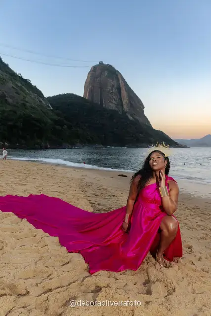 Portrait of a woman with a golden crown and a pink satin dress at Praia Vermelha at sunset