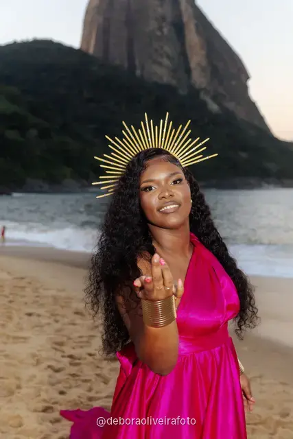 Portrait of a woman with a golden crown and a pink satin dress at Praia Vermelha at sunset