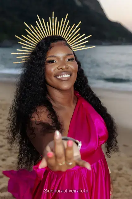 Woman in a pink dress and golden crown on Praia Vermelha at sunset in Rio de Janeiro