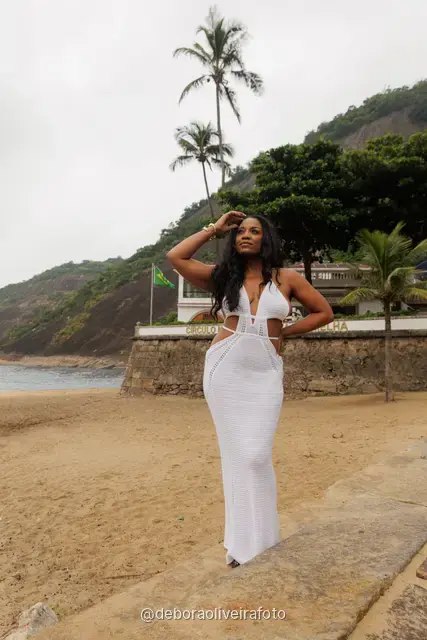 Woman in a white crochet dress at Praia Vermelha with Sugarloaf Mountain in the fog, Rio de Janeiro