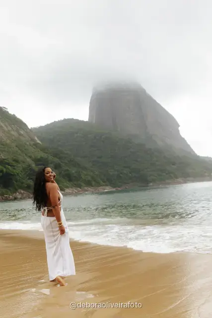 Woman in a white crochet dress at Praia Vermelha with Sugarloaf Mountain in the fog, Rio de Janeiro